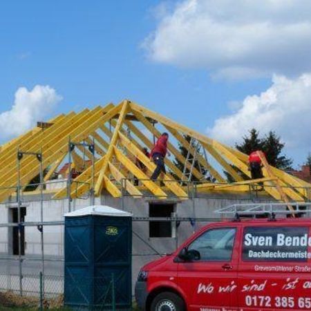 Dachgerüst aus Holz mit einem rotem Auto davor - Dachdeckerei Bender